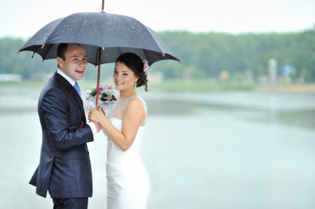 Wedding day rain, couple under black umbrella