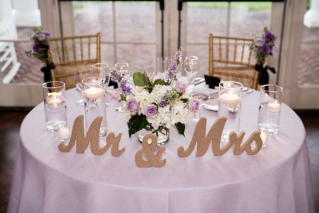 Round table for two with white table cloth Mr and Mrs signs on table and 2 wooden chairs