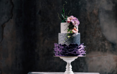 Closeup of white wedding cake with flowers on top. cake on the cake-shelf. white milk cream. cake decorated with pink and purple flowers