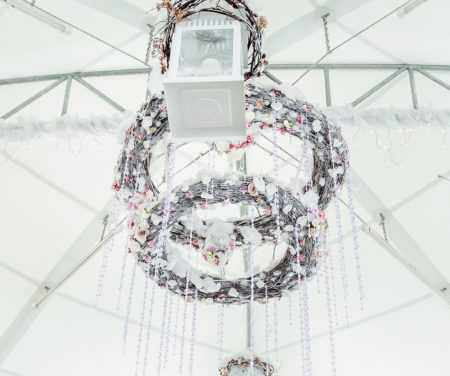 Chandelier made of white flowers hangs under the white tent