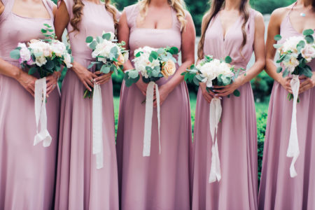 Glorious bridesmaids in pink dresses holding beautiful bunch of flowers