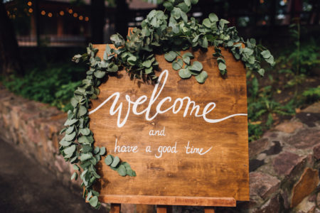 Handmade wooden board with welcome sign on it decorated with eucalyptus. Wedding. Reception.