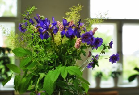 Bunch of Meadow cranes-bill in a vase as decoration for a wedding celebration or ceremony. A beautiful bouquet of purple flowers as decor at an event venue. Decorative plants in a building