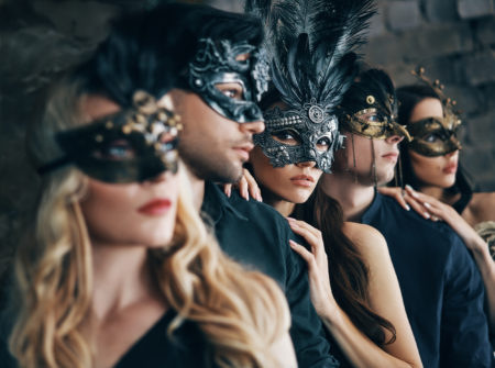Group of people in masquerade carnival mask posing in studio. Beautiful women and men wearing venetian mask. Fashion, party, friends concept