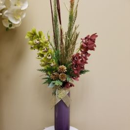Tall centerpiece with red and green orchids and winter greenery