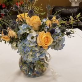 Centerpiece of blue hydrangeas and orange roses