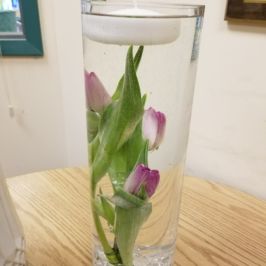 Centerpiece of pink tulips in water under floating candle
