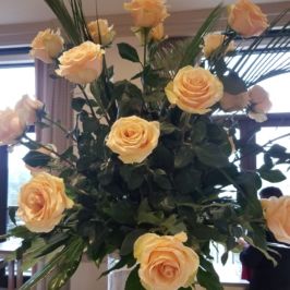Tall centerpiece of pastel roses and greenery