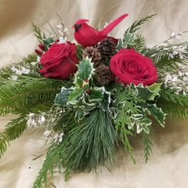Arrangement of red roses, holly, winter greenery and cardinal decoration
