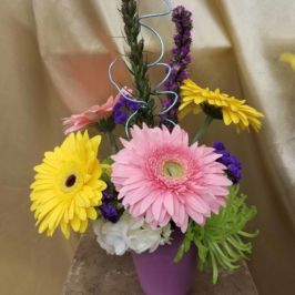 Pink, yellow and green flowers in a purple vase