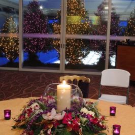 Centerpiece of bright winter flowers around a candle