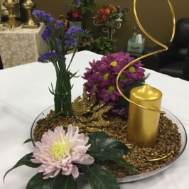 Sample centerpiece of a gold candle and flowers
